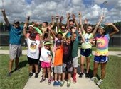 A group of kids and counselors from camp jumping with their hands up